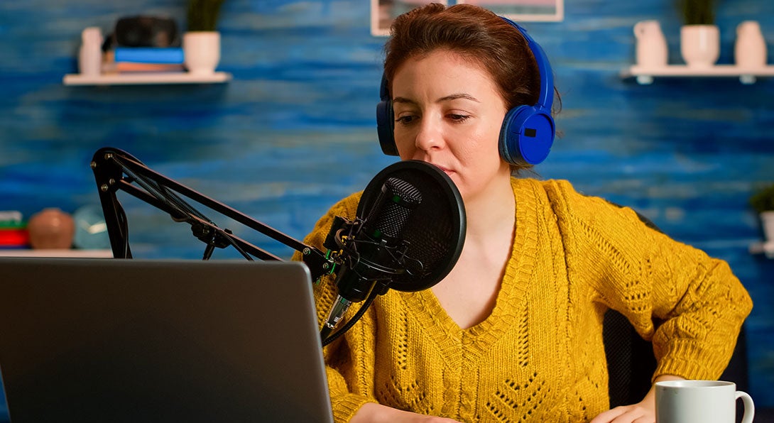 A female student speaks on a microphone connoting a podcast influencer