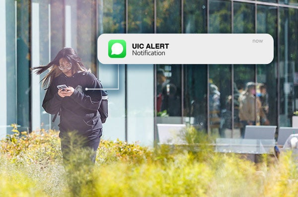 A student receiving a UIC ALERT text message while walking on campus